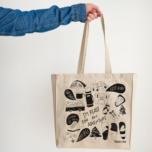 Hand holding whimsy canvas tote with playful drawings
